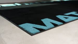 Nahaufnahme einer Logomatte mit blauem Schriftzug von EDER Mat Couture. 